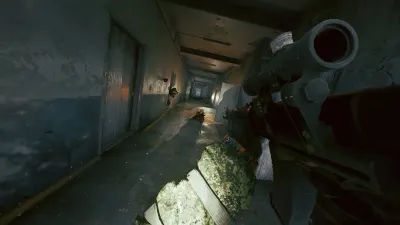 An operative moving down a dim concrete corridor with a rifle raised